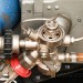 Detailní pohled na tlakovou láhev s ventilem (10), redukční ventil (12), ruční přídavkový ventil (18) a uzavírací ventil k manometru (19).